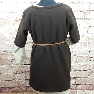 May include: A brown long-sleeved dress with a beige under layer. The dress has a brown belt around the waist.