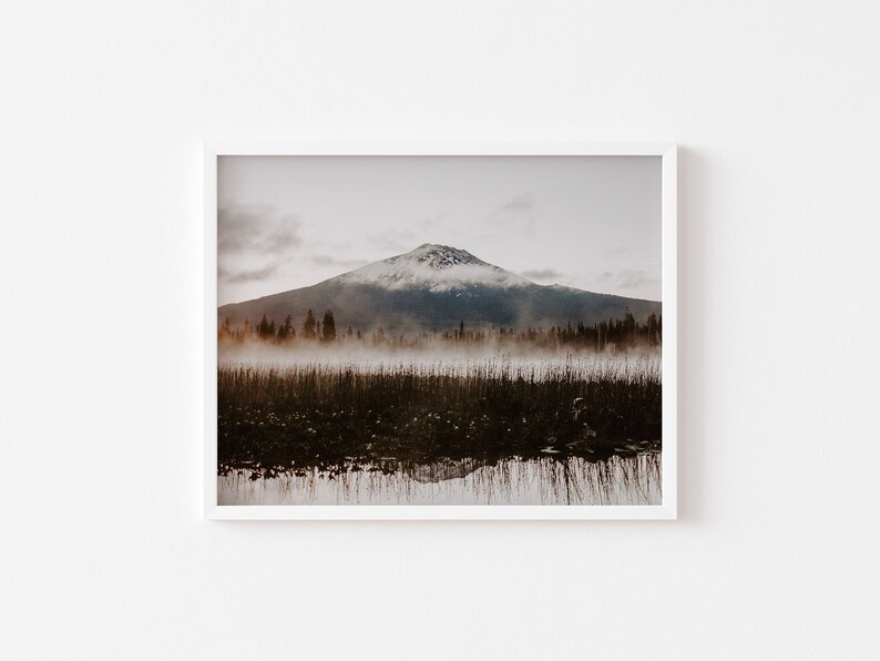 A framed photograph of Mt. Bachelor at sunrise with trees and fog in the foreground