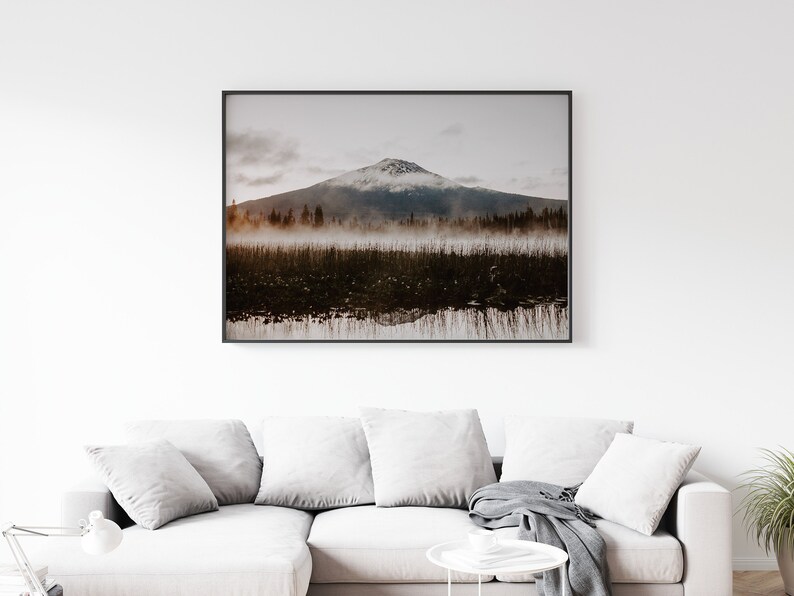 A photograph of Mt. Bachelor at sunrise with trees and fog in the foreground