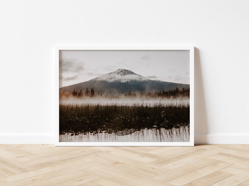 A photograph of Mt. Bachelor at sunrise with trees and fog in the foreground