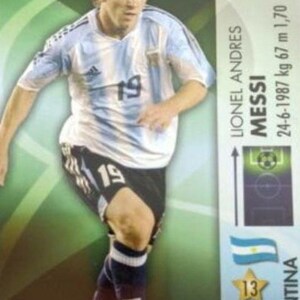 May include: A trading card featuring Lionel Messi in an Argentina soccer uniform. The card shows Messi in action, wearing a light blue and white striped jersey with the number 19. The card includes the player's name, birthdate, height (1.70 m), and weight (67 kg).