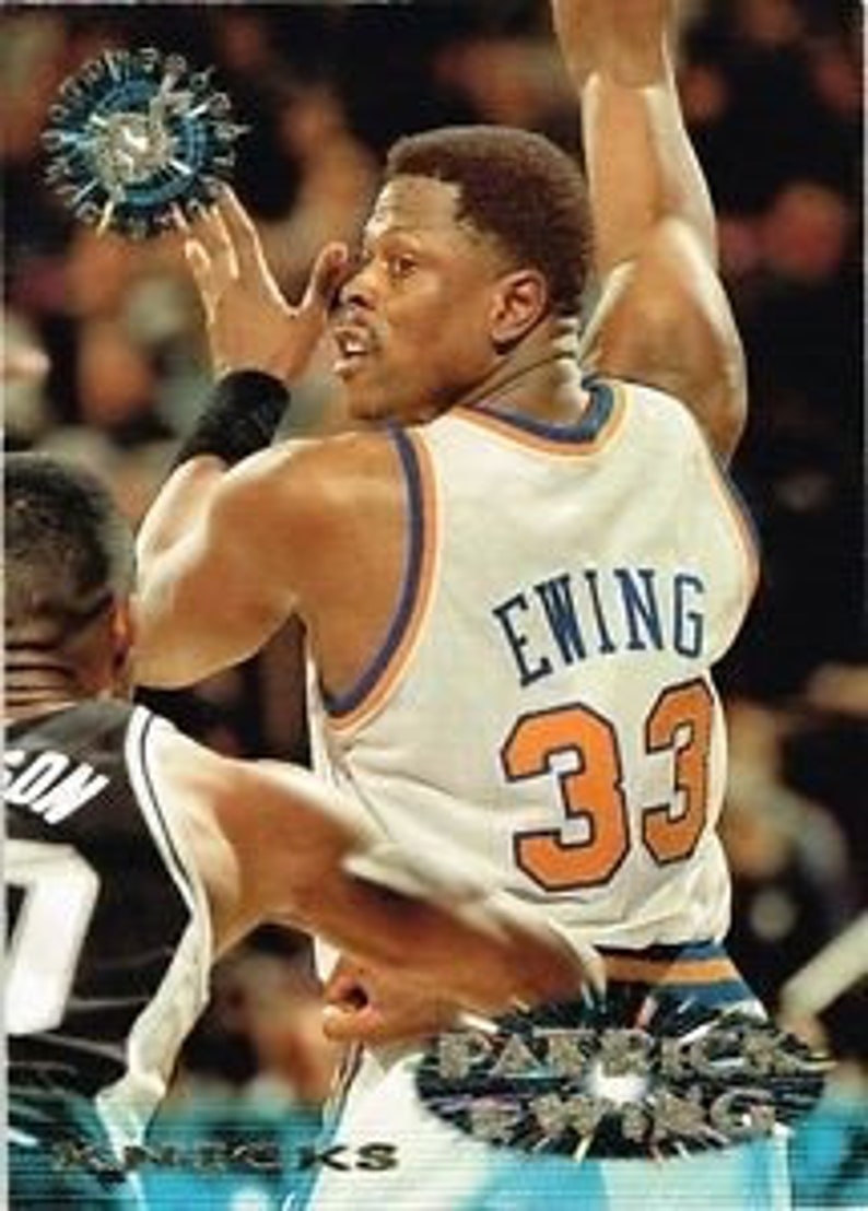 Puede incluir: Una tarjeta de baloncesto plateada y azul con Patrick Ewing, un ex jugador de la NBA, vistiendo una camiseta azul y naranja con el n&uacute;mero 33. La tarjeta tiene un dise&ntilde;o hologr&aacute;fico y una estrella plateada.