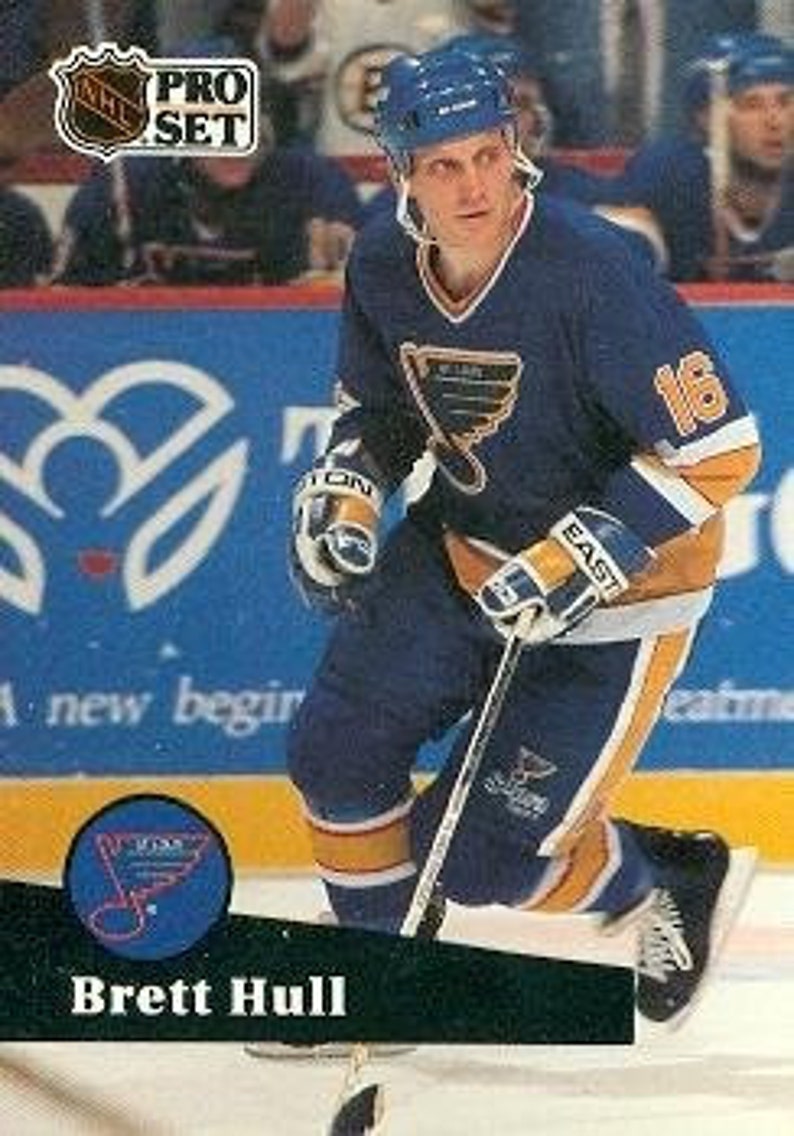May include: A hockey trading card featuring Brett Hull, a player for the St. Louis Blues, wearing a blue and yellow jersey with the number 16. The card is from the 1991-92 Pro Set series.