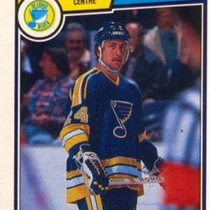 May include: A hockey player wearing a blue and yellow jersey with a blue bird logo on the front. The jersey has the number 44 on the front. The player is holding a hockey stick and is looking at the camera.