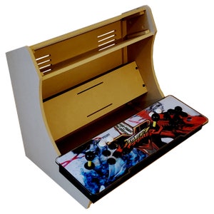 May include: A light wood-colored arcade cabinet with a white exterior. The control panel features a Street Fighter design with joysticks and buttons. The cabinet has a curved top and a shelf.