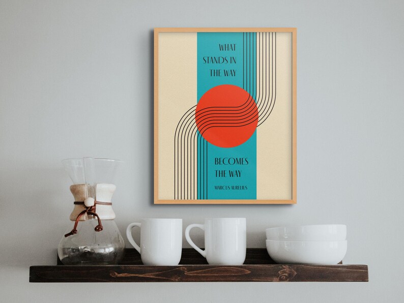 May include: A framed print with a teal background and a red circle with black lines. The text reads "What stands in the way becomes the way" - Marcus Aurelius.