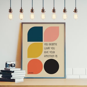 Może przedstawiać: Wydruk w ramie z geometrycznym wzorem w odcieniach niebieskiego, ż&oacute;łtego, r&oacute;żowego i czarnego. Wydruk zawiera tekst "You become what you give your attention to."