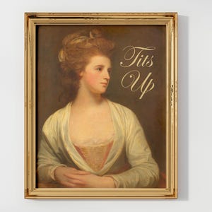 May include: A framed painting of a woman with a gold frame. The woman is wearing a white dress and has her hair up. The text "Tits Up" is written in gold lettering on the painting.