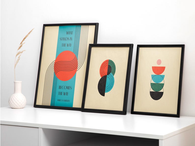 May include: Three framed abstract art prints with geometric shapes and text. The first print has a red circle with black lines and the text "What stands in the way becomes the way". The second print has a green and blue circle with a black circle inside. The third print has a stack of colorful semi-circles.