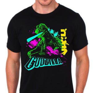 May include: Black t-shirt with a neon green, blue, and pink graphic of Godzilla with the Japanese text "ゴジラ" and the word "GODZILLA" underneath.