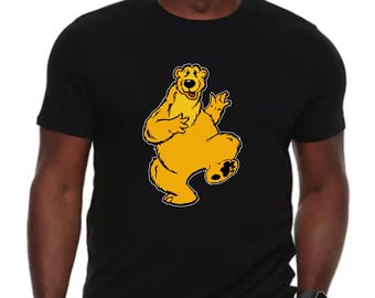 May include: A black t-shirt with a yellow cartoon bear wearing a smile and waving. The bear is in a dancing pose.
