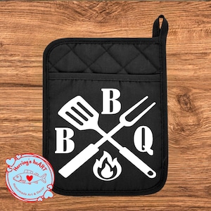 May include: Black quilted oven mitt with a white BBQ design. The design includes a spatula and fork crossed over a flame, with the letters "B", "B", and "Q". A small logo with text and a fish is in the lower left corner.