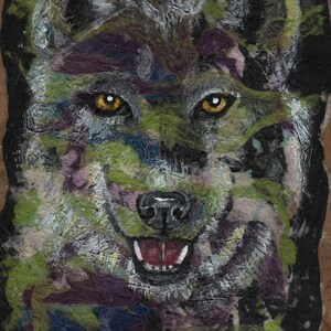 May include: A close-up of a wolf's face painted in a colourful abstract style. The wolf's fur is painted in shades of green, purple, and black, with white highlights. The wolf's eyes are a bright yellow, and its mouth is open in a snarl.