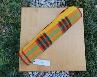 May include: A yellow, green, red, and black striped fabric with a tag that reads "WRAP - GOOD HEALTH".