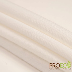 Puede incluir: Primer plano de una tela de algodón orgánico blanco, doblada en varias capas. La tela es suave y lisa, con una textura sutil. La tela está etiquetada con "PROECO ORGANIC FABRICS".