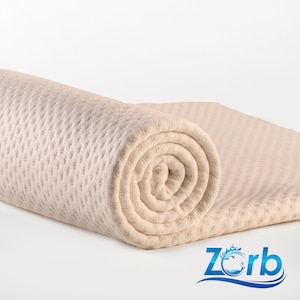 May include: A rolled up beige waffle weave towel with a textured surface. The towel is rolled up tightly and is lying on a white surface.
