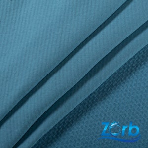 May include: A close-up of a blue fabric with a textured pattern. The fabric is folded in thirds, with the top layer folded over the bottom two layers. The fabric is soft and smooth to the touch.
