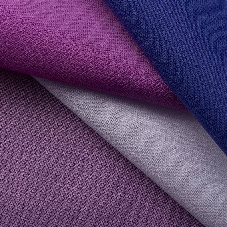 May include: Close-up of three fabric swatches in shades of purple, blue, and gray. The fabric has a textured, woven appearance.