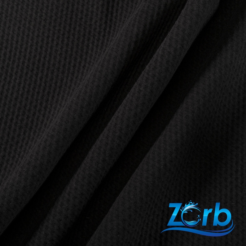 May include: Black waffle knit fabric with a subtle texture. The fabric is folded in a diagonal pattern. The Zorb logo is visible in the bottom right corner.