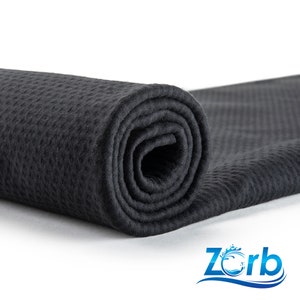Puede incluir: Una toalla de tejido de waffle negro enrollada. La toalla est&aacute; hecha de un material suave y absorbente, ideal para secarse despu&eacute;s de un entrenamiento o un ba&ntilde;o.
