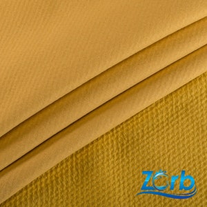 May include: Close-up of a mustard yellow fabric with a textured waffle weave. The fabric is folded in thirds, showing the texture of the material.