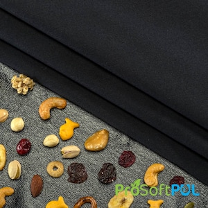 May include: A variety of snacks, including pretzels, nuts, dried fruit, and cereal, are scattered on a silver background. A black fabric is draped over the top of the snacks.