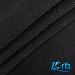 May include: Black fabric with a textured, woven pattern. The fabric is folded in thirds, with the bottom fold showing the logo "Zorb" in blue with a wave design.
