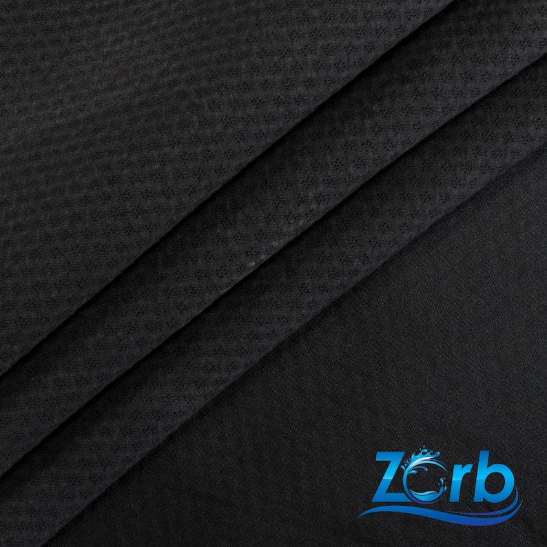 May include: Black fabric with a textured, woven pattern. The fabric is folded in thirds, with the bottom fold showing the logo "Zorb" in blue with a wave design.