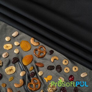 May include: A variety of snacks, including pretzels, dried fruit, nuts, and cereal, are scattered on a silver surface. The snacks are arranged in a semi-circle shape, with a black fabric background.