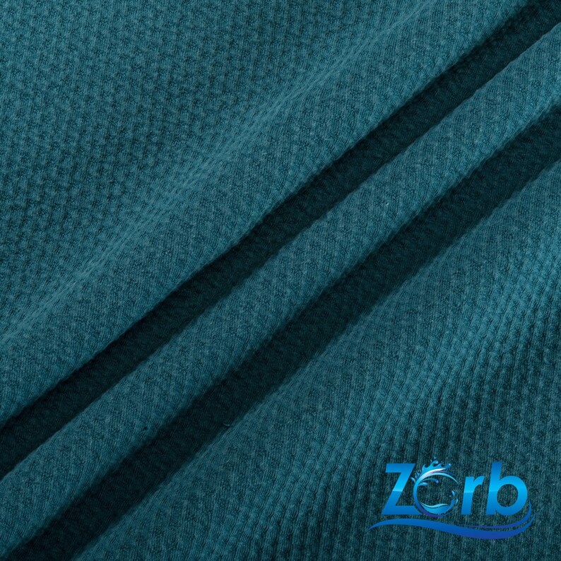 May include: Teal textured fabric with a subtle waffle weave pattern. The fabric is folded in a diagonal pattern, creating a soft, drapey look.