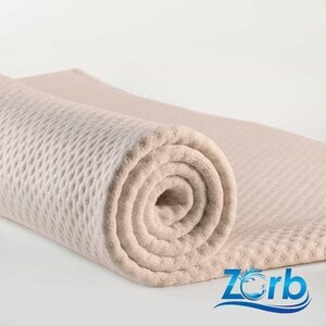 May include: A beige, quilted, rolled-up mattress pad with the word "Zorb" printed on the bottom right corner.