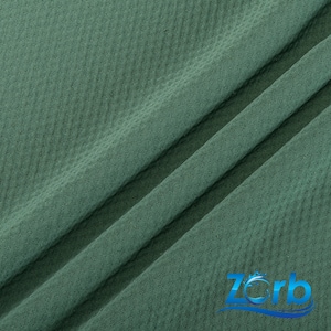 Puede incluir: Primer plano de una tela verde texturizada con un sutil patr&oacute;n de diamante. La tela es suave y tiene un ligero brillo.