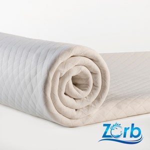 May include: A rolled up white quilted mattress topper with a diamond pattern. The topper is made by Zorb.