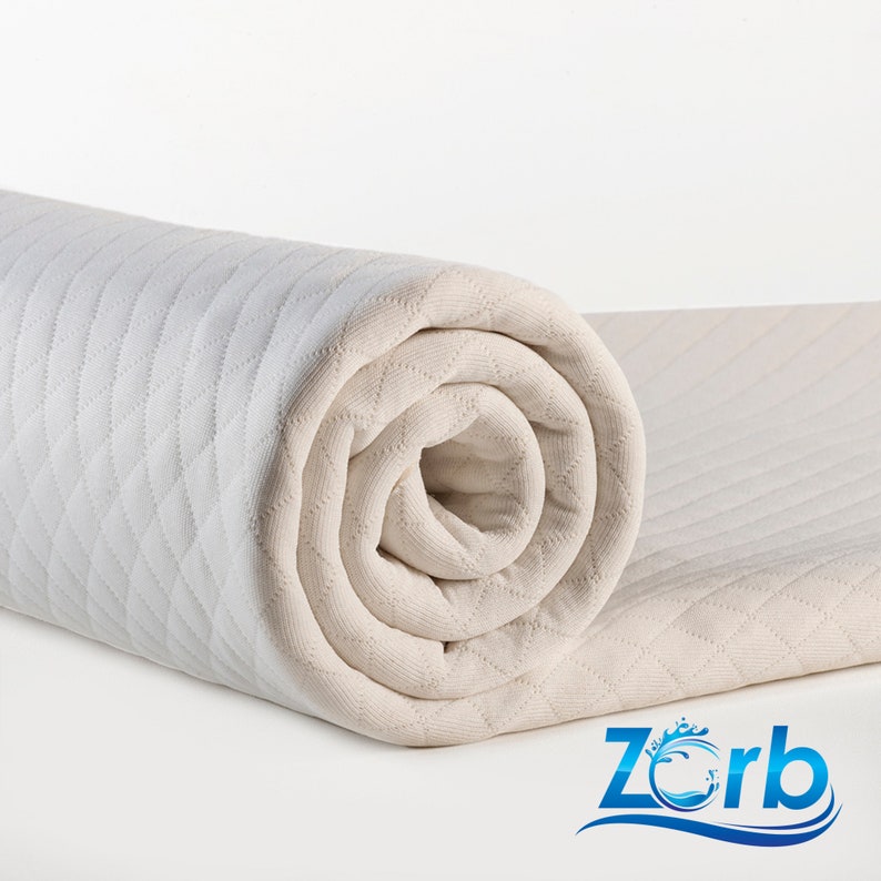 May include: A rolled up white quilted mattress topper with a diamond pattern. The topper is made by Zorb.