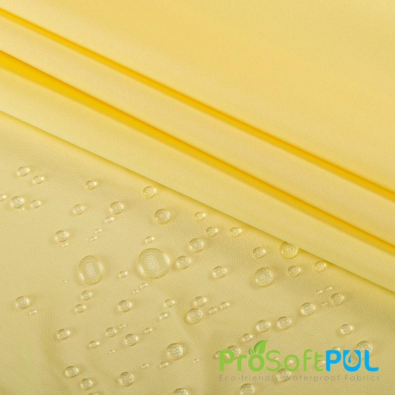 May include: Yellow fabric with water droplets on the surface. The fabric is smooth and has a slight sheen. The text "ProSoftPUL Eco-friendly Waterproof Fabrics" is visible in the lower right corner of the image.