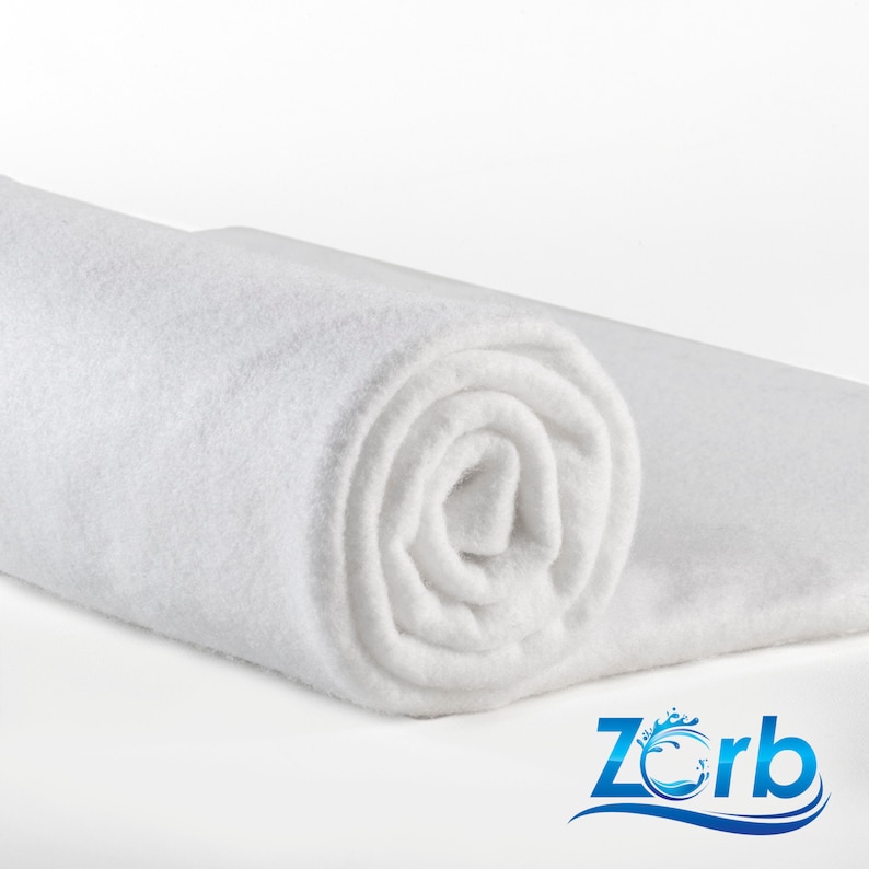 May include: A white, rolled-up piece of fabric. The fabric is soft and fluffy, and it is perfect for use in a variety of crafts and projects. The fabric is made by Zorb.
