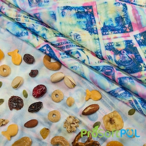 May include: A white fabric with a variety of snacks scattered on it. The fabric has a blue and pink pattern of US dollar bills. The snacks include goldfish crackers, pistachios, dried cranberries, pretzels, and granola.