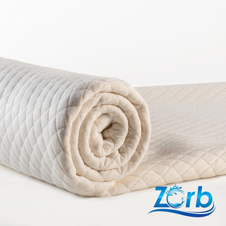 May include: A rolled up white quilted mattress topper with a diamond pattern. The topper is made by Zorb.