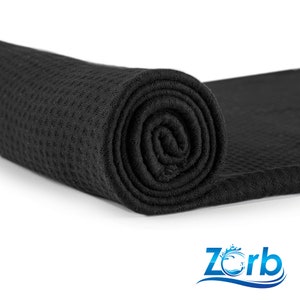 May include: A black waffle weave towel rolled up, with the brand name "Zorb" printed in blue and white on a white background.