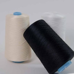 May include: Three spools of thread, one white, one beige, and one black.