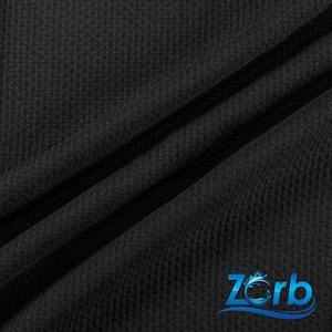 May include: Black waffle knit fabric with a subtle texture. The fabric is folded in a way that shows the texture and drape.
