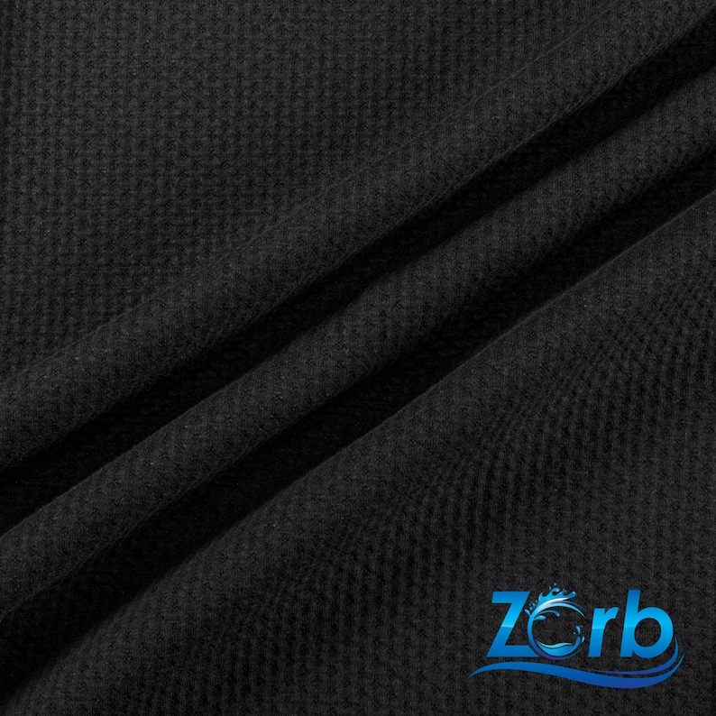 May include: Black waffle knit fabric with a subtle texture. The fabric is folded in a way that shows the texture and drape.