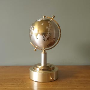 Distributore di sigarette a forma di globo in ottone di metà secolo con carillon funzionante.