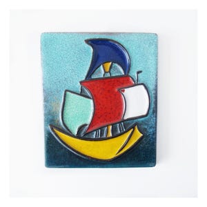 Può includere: Piastrella in ceramica rettangolare con un design di barca a vela stilizzato. La barca ha uno scafo giallo, vele rosse e bianche e una vela blu. Lo sfondo è una sfumatura di blu e turchese.