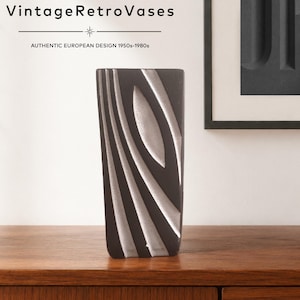 May include: A tall, rectangular dark gray vase featuring a textured, light gray abstract pattern of curved lines and an oval shape. The text "VintageRetroVases" and "AUTHENTIC EUROPEAN DESIGN 1950s-1980s" is printed in black at the top of the image.