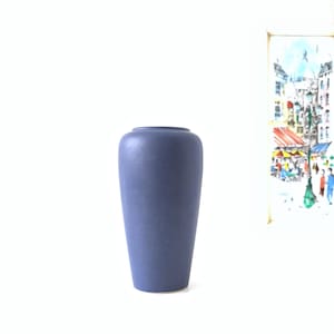 Puede incluir: Un jarrón de cerámica azul, alto y delgado, con un acabado liso y mate.