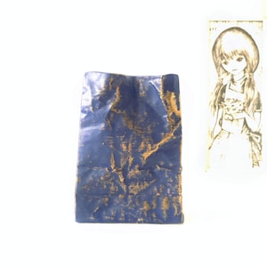 Puede incluir: Una bolsa de papel azul y dorada con textura arrugada.