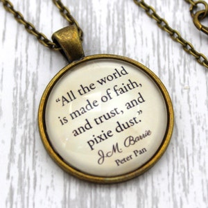 May include: A bronze necklace with a round pendant featuring a quote from J.M. Barrie's Peter Pan: "All the world is made of faith, and trust, and pixie dust."
