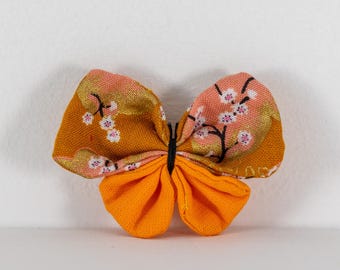 Butterfly brooch in Japanese cherry blossom fabric on an orange background