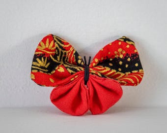 Butterfly brooch in Japanese fabric with black and gold patterns on a red background